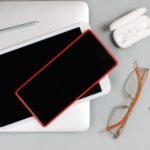 Mobile phone, tablet, earphones and glasses near laptop