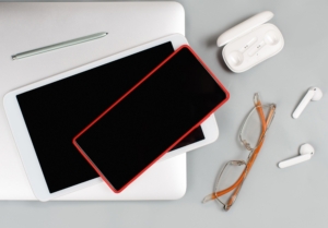 Mobile phone, tablet, earphones and glasses near laptop