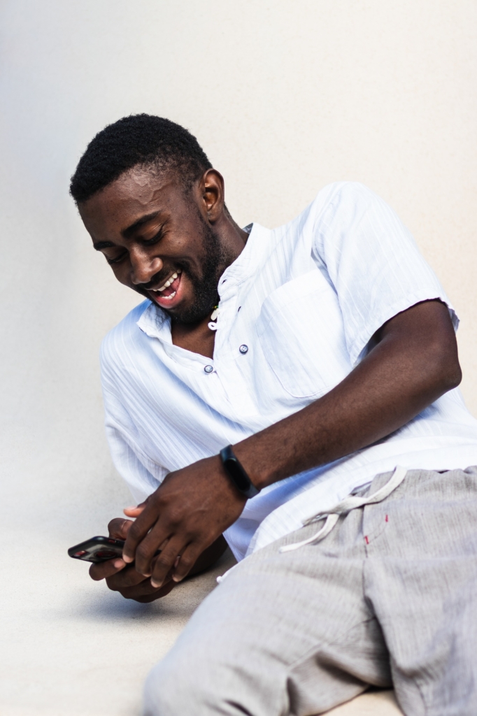 Black man laughing while browsing on mobile phone